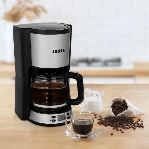 TESLA Coffeemaster ES300, čierny kávovar na prekvapkávanú kávu s digitálnym časovačom a plnou kanvicou čerstvej kávy na drevenom kuchynskom pulte.