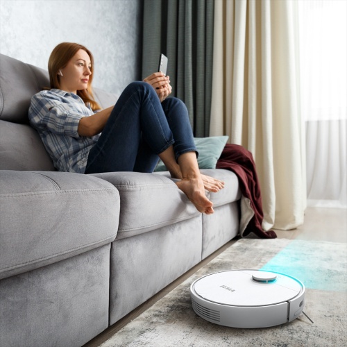 Žena relaxujúca na pohovke ovláda robotický vysávač TESLA RoboStar iQ550 pomocou diaľkového ovládača.