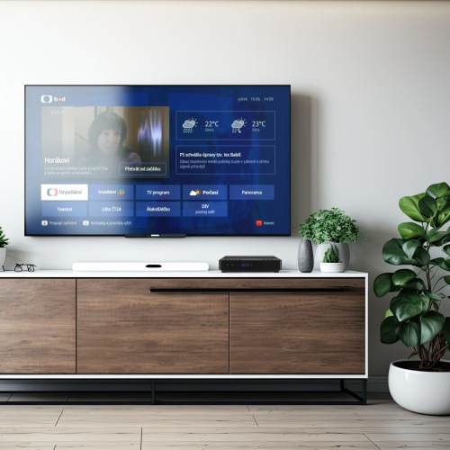 Set-top box TESLA HYbbRID TV TH210 na stole pod televízorom so zobrazením archívu českej televízie